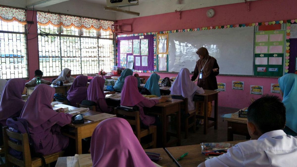 Seorang guru sedang mengajar siswa di kelas dengan penuh antusias.