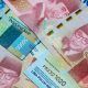 Ilustrasi pencairan gaji ke-13 dan THR bagi PNS tahun 2025 dengan tumpukan uang rupiah.